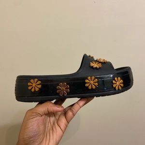 Black platform Crocs with Gold flower detailing.